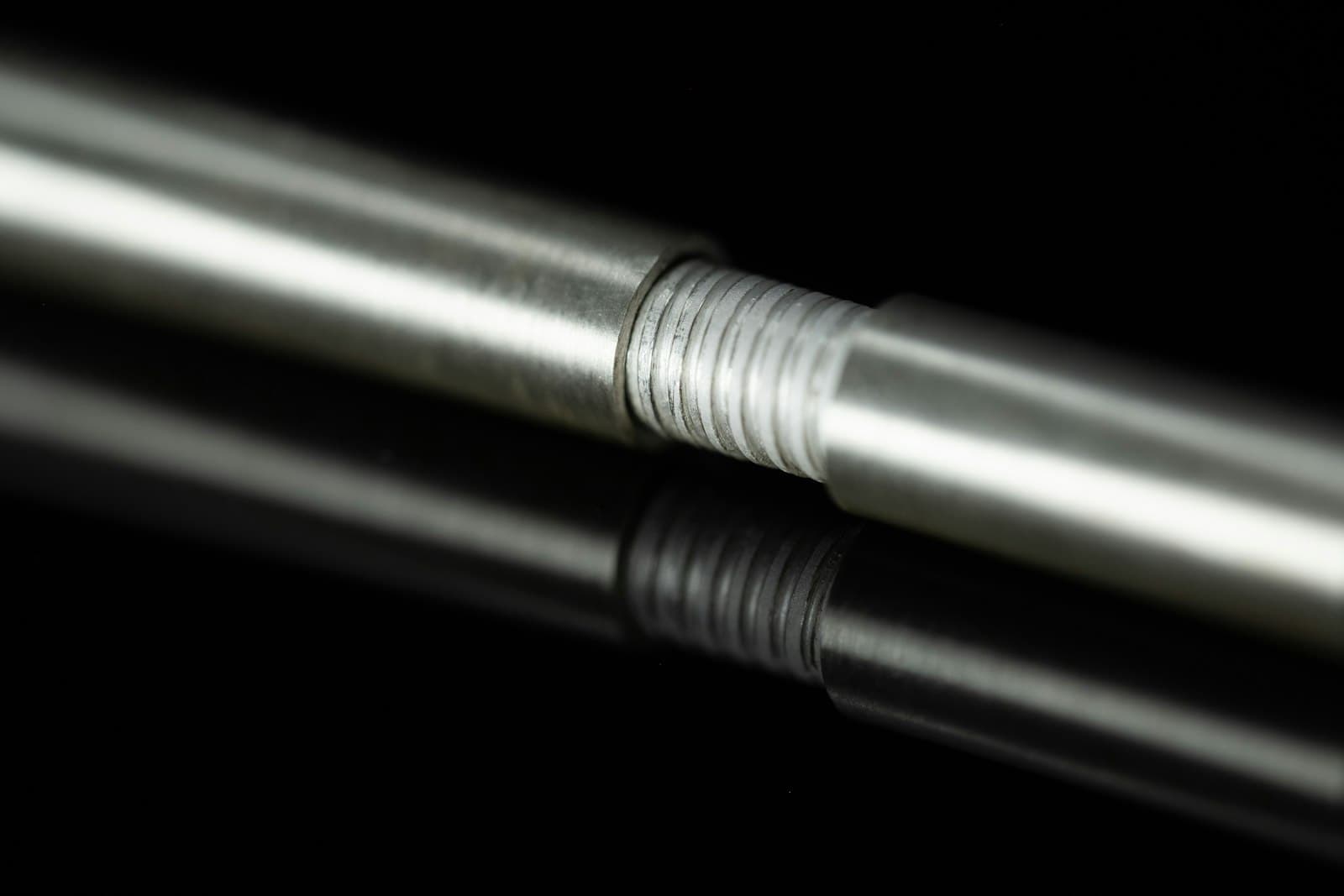 A threaded rod reflecting on a dark surface